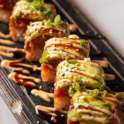 Spicy Tuna Crispy Rice roll topped with avocado and sauces.