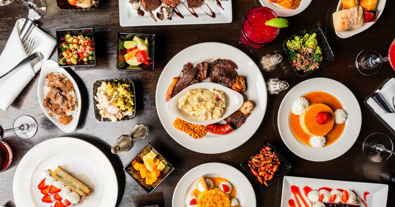 A table spread with assorted  food plates and drinks, overhead view
