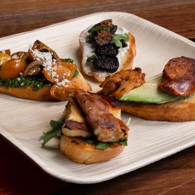 Four assorted bruschetta with various toppings on a tray.