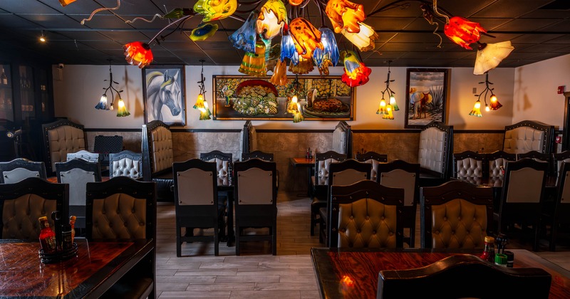 Inside, dining area, colorful glass chandeliers, tufted chairs, and artwork on the walls