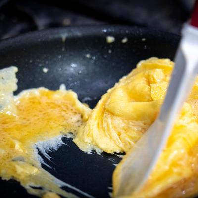 Scrambled eggs cooking in a black skillet.
