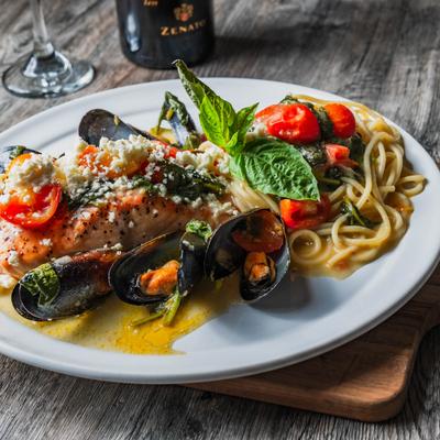 Grilled salmon with pasta, spinach, mussels, tomatoes, cheese, and mint.
