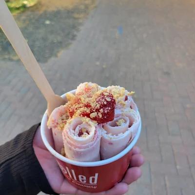 Rolled ice cream cup with berries held outdoors.