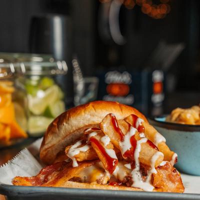 Bacon cheeseburger with fried potato strips and sauce drizzle.