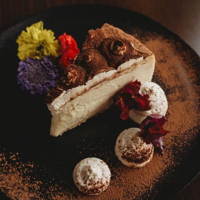 Tiramisu cheesecake dusted with cocoa powder, garnished with flowers.