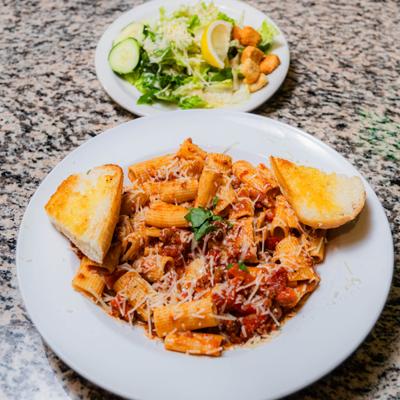 Rigatoni Bolognese served with garlic bread and a side salad with croutons.