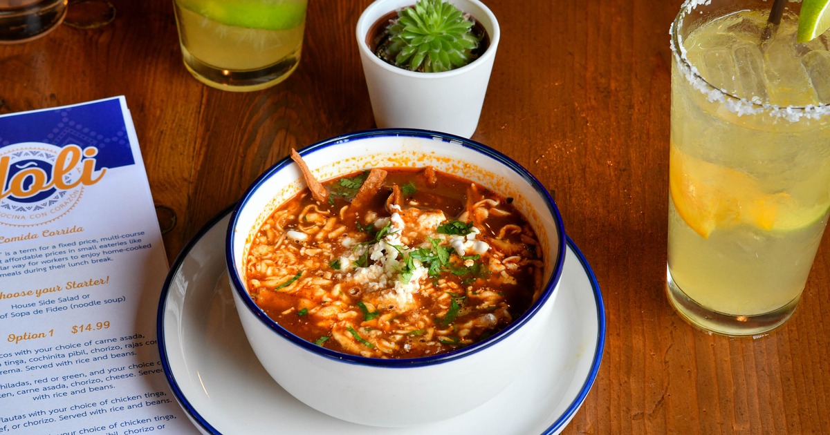 Bowl of tortilla soup with a drink