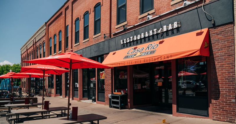Exterior, front view to the restaurant, tables and chairs, parasols across the walking way