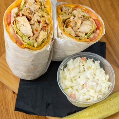 Buffalo Chicken Wrap served with sides of coleslaw and a pickle spear.