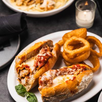 Chicken Parmigiano sandwich served with onion rings.