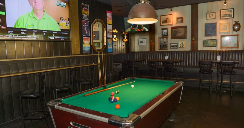 Interior, billiards table with high seating around it, large screen TV on the wall