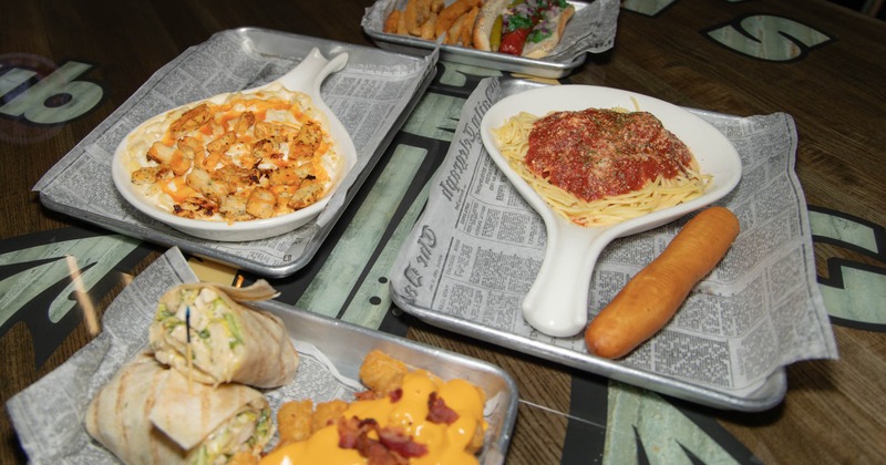 Various dishes on a table including baked macaroni and cheese, spaghetti, wrap, and a hot dog