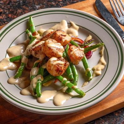 A dish of Seared Sea Scallops served over green bean medley with ginger miso dressing