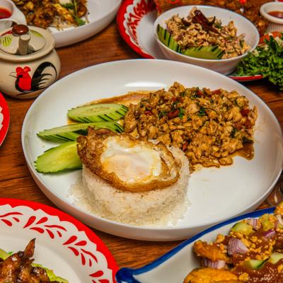 Thai Basil dish served with rice topped with fried egg and cucumber slices.