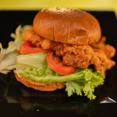 Fried Chicken Sandwich with lettuce and tomato, served on a plate.