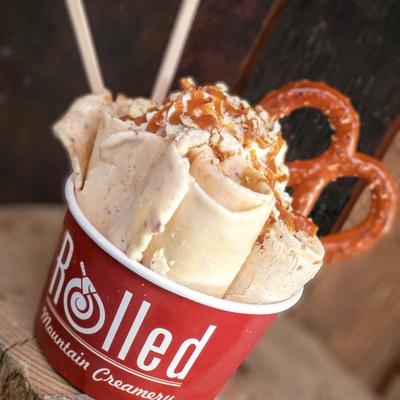 Creamy dessert topped with pretzel twists in a red cup.