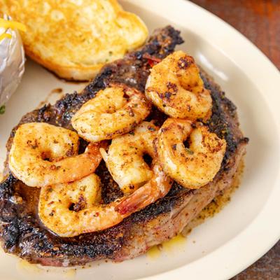 Grilled steak topped with shrimp, close-up.