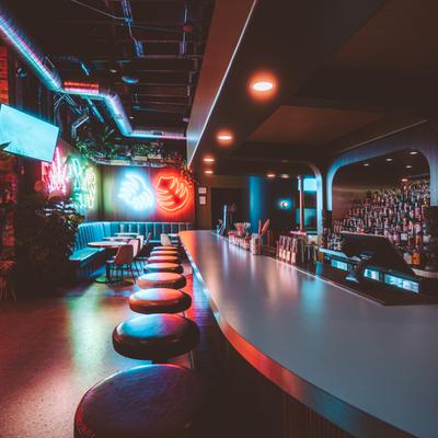 Bar area with seating lit by neon lights on the wall