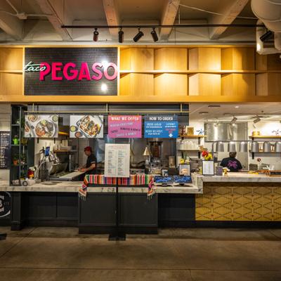 A Mexican taco counter stall named Taco Pegaso indoors.