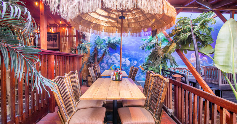Exterior, decorated seating area with palm trees and a mural