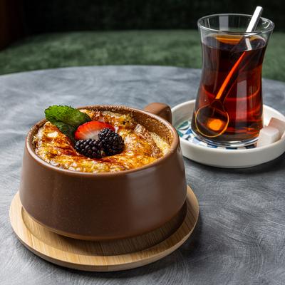 Creme Brulee topped with berries and served with a cup of tea.