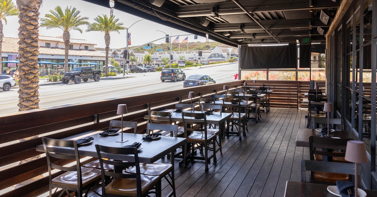 Outdoor dining area of a restaurant with tables and palm trees