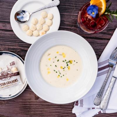 Clam Chowder served with crackers and a drink.