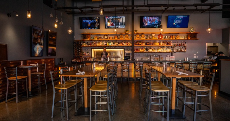 Interior, high top tables and chairs, bar area in the back