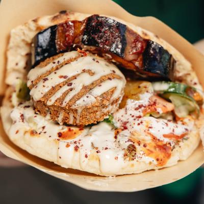 Falafel pita sandwich with fried eggplant, fresh vegetables and tahini sauce.