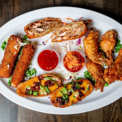 Appetizer platter with potato skins, wings, mozzarella sticks, and sauces.