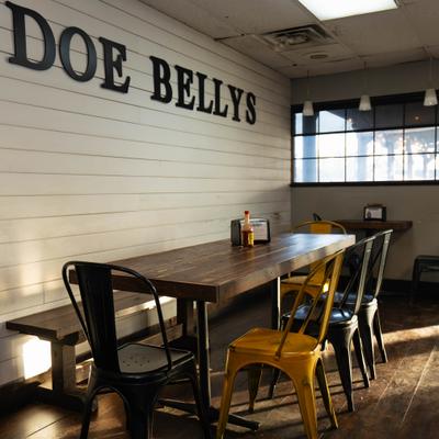 Interior with long wooden table, bench, chairs and signage on the wall.