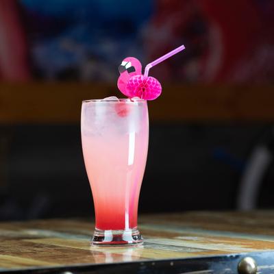 A vibrant pink cocktail with a straw garnished with a small flamingo.