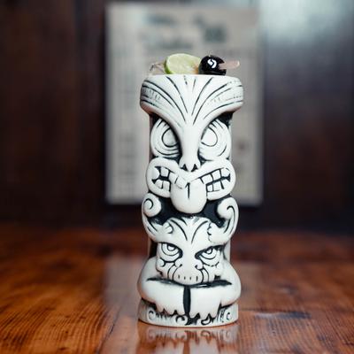 A cocktail served in a white tiki mug.
