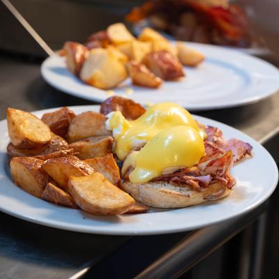 Eggs Benedict with hollandaise sauce and roasted potatoes on the side.