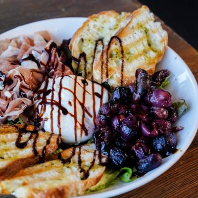 Ball of burrata drizzled with a balsamic glaze, served with toast.