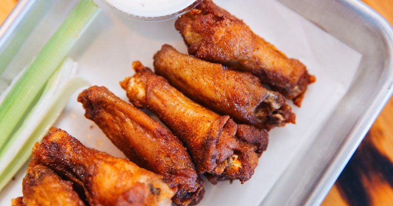 Crispy chicken drumettes with celery and ranch on a metal tray