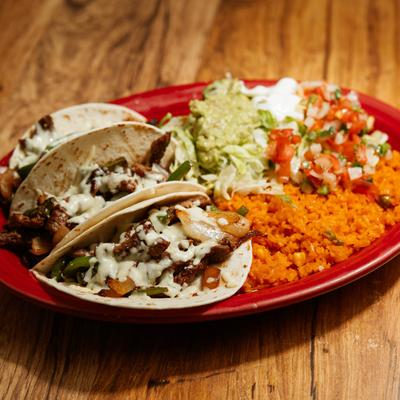 Tacos served with rice, guacamole, fresh salsa, and sour cream.