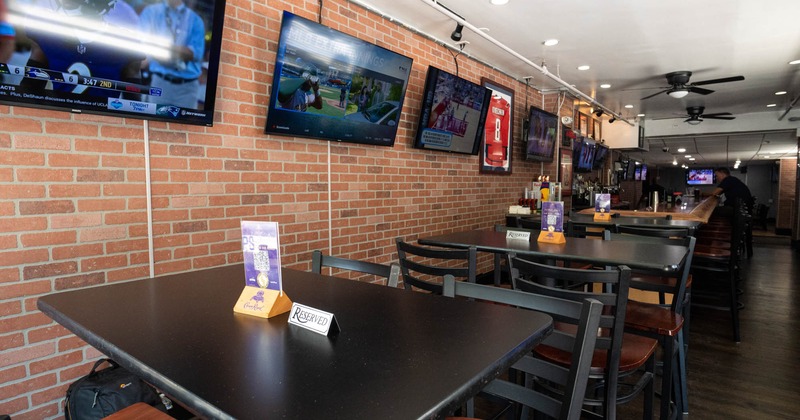 Tables for sitting against the wall with TV screens