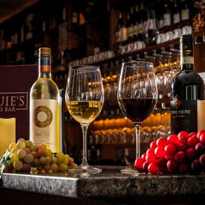 Wine bottles and glasses arranged beside colorful grapes.