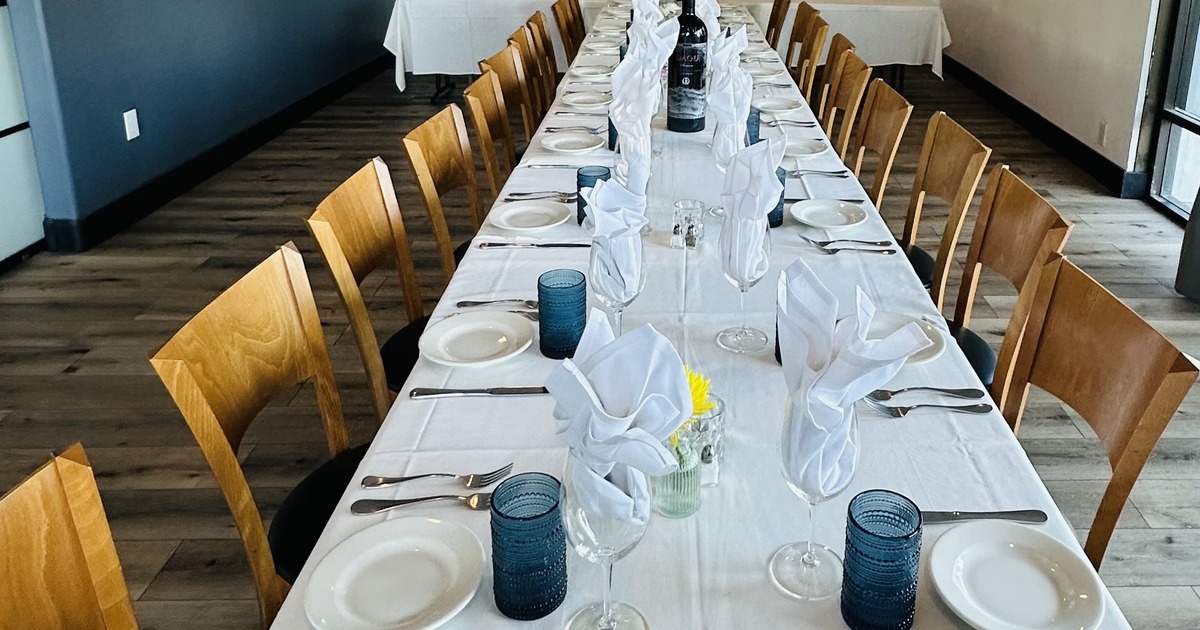Long dining table set with plates, glasses, napkins and cutlery