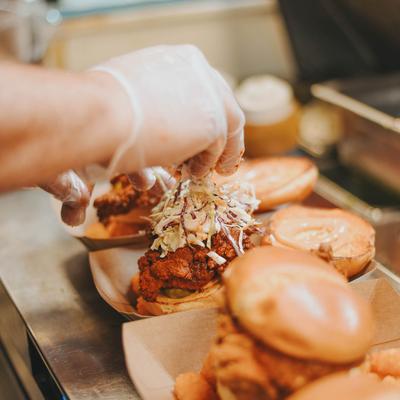 Chef preparing Nashville hot chicken sandwiches, close-up.