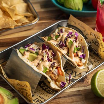 Shrimp Tacos topped with slaw, avocado slices, and chipotle aioli.
