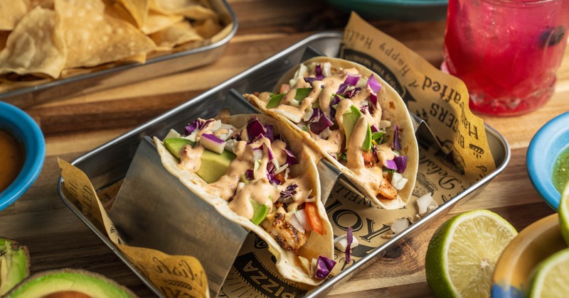 Two Shrimp Tacos served on a metal tray lined with paper