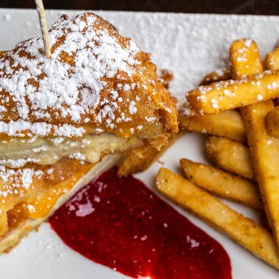 Fried Monte Cristo sandwich dusted with powdered sugar, served with fries and strawberry jam.