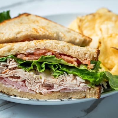 Ham, Turkey, and Swiss cheese sandwich with chips.