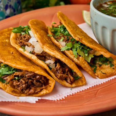 Birria tacos served with dipping broth.