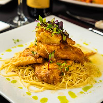 Chicken and shrimp Francese served over angel hair pasta with microgreen garnish.
