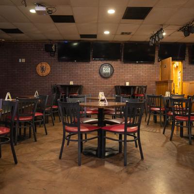 Interior with tables, chairs, and TVs mounted on a brick wall.