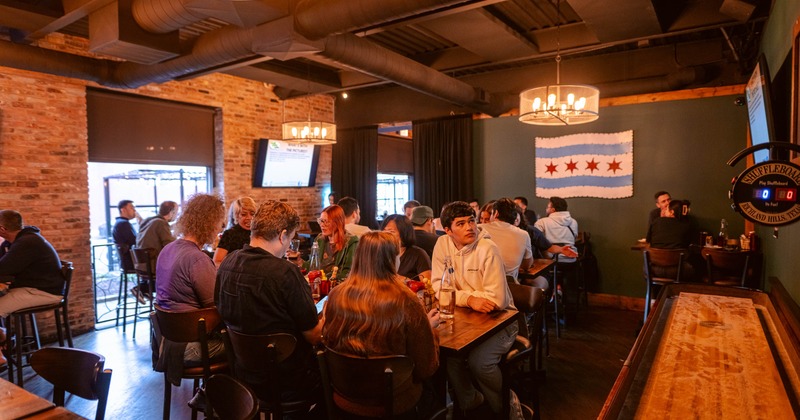 Interior featuring exposed brick walls, industrial ceiling pipes, and a Chicago flag