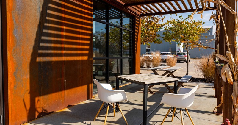 Exterior, covered seating area, tables, chairs, sunlight, parked cars